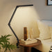 Modern LED desk lamp on a bedside table with books and decor items, next to a bed.