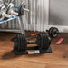 Pair of adjustable dumbbells on a wooden floor with a weight plate set in the background.