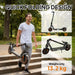 Man carrying lightweight black electric scooter with orange accents and quick folding design outdoors