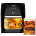 Black air fryer with a cooked chicken inside, next to a cookbook on a white background