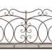 Antique brown wrought iron garden bench with decorative scrollwork backrest on white background