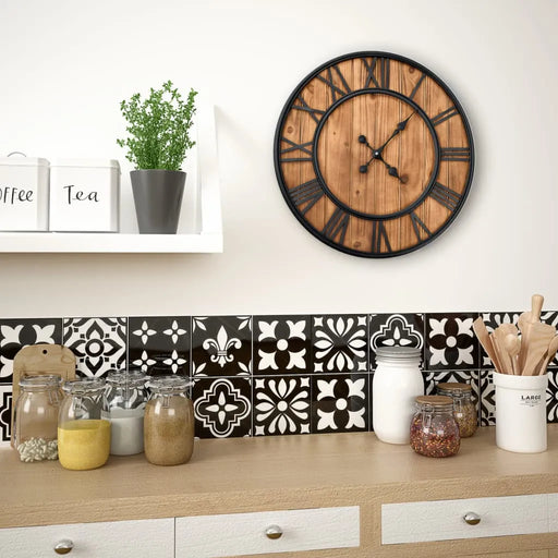 Wooden clock on a wall above a kitchen counter with decorative tiles and jars.