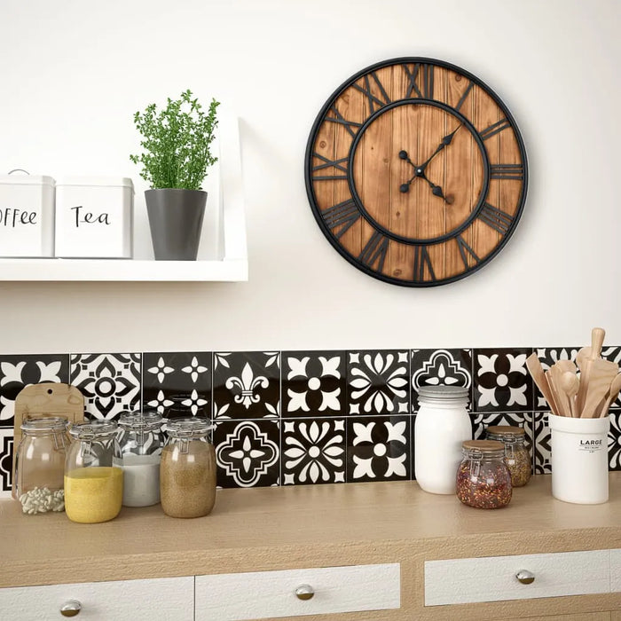 Wooden clock on a wall above a kitchen counter with decorative tiles and jars.