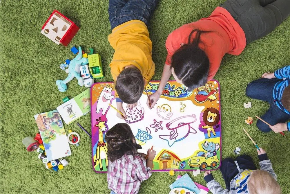 Kids and adult drawing on Aqua Doodle water mat with magic pens and animal stencils on green rug
