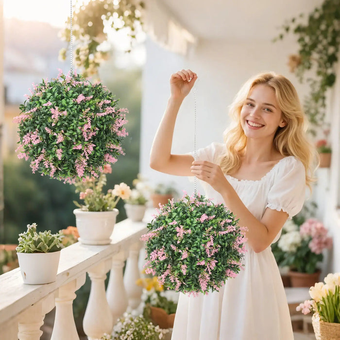 Smiling woman in white dress holding artificial lavender topiary balls on sunny balcony with potted plants