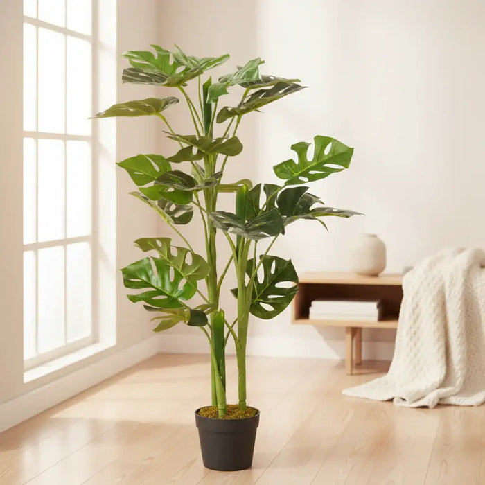 Potted artificial monstera plant in a plush white lounge setting