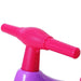 Pink handlebar of a violet kids' balance bike with plastic finish, close-up view