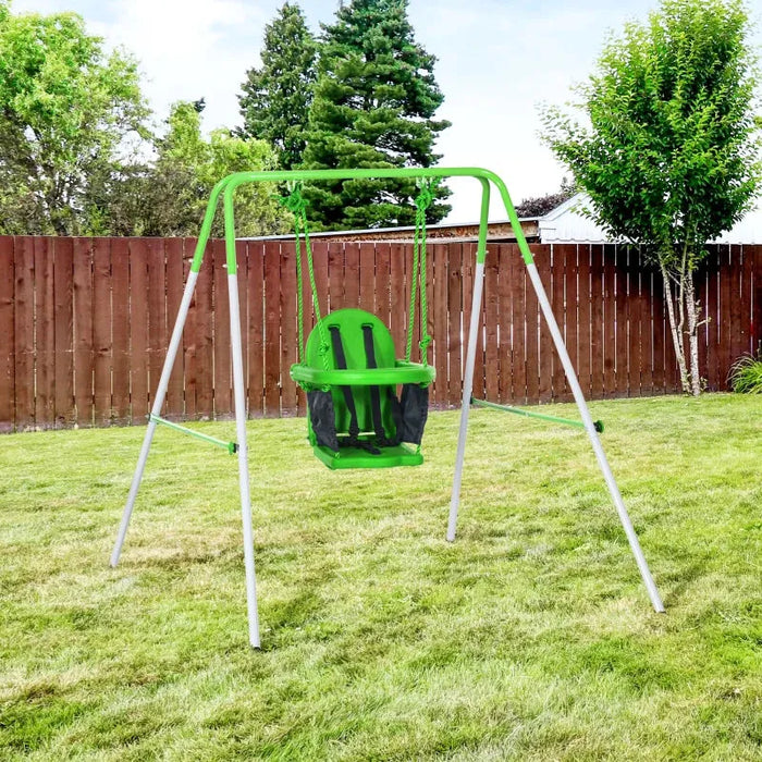 Green toddler swing with safety belt on metal frame in grassy backyard