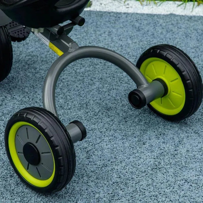 Close-up of baby trike rear wheels with green accents on textured outdoor surface