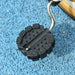 Close-up of black tricycle pedal on blue textured ground