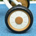 Close-up of baby trike wheel with beige hub on blue textured ground