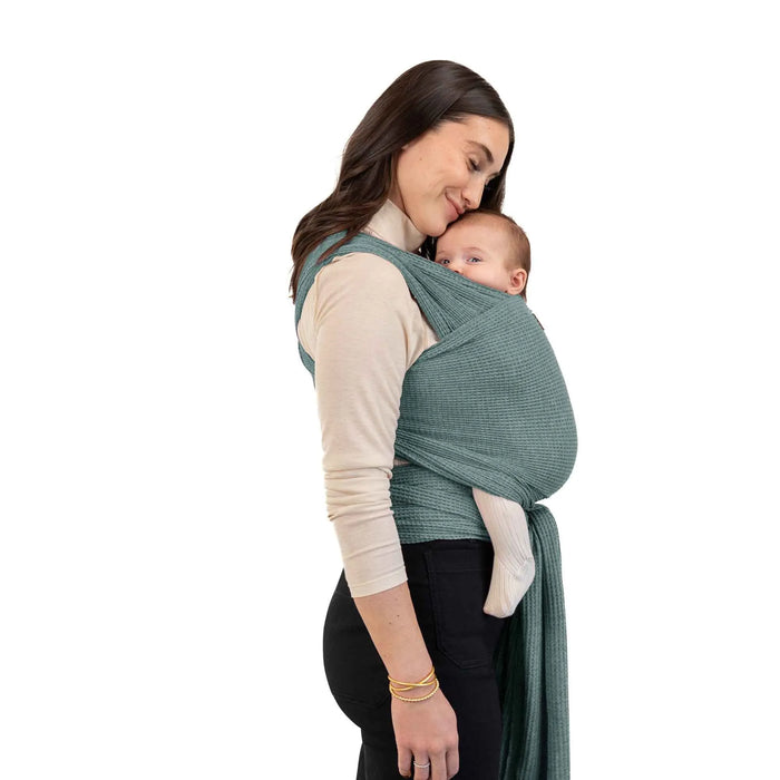Woman wearing a baby in a green wrap carrier on a white background