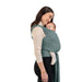 Woman wearing a baby in a green wrap carrier on a white background