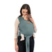 Woman holding a baby in a teal Moby wrap carrier against a white background