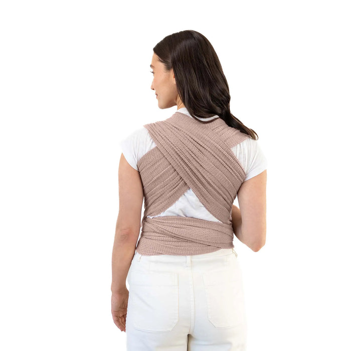 Woman wearing a brown woven wrap carrier on a white background