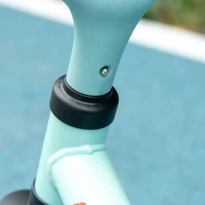 Close-up of adjustable balance bike seat post with blue frame on outdoor track