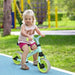 Toddler riding a mint green balance bike with EVA wheels outdoors on a sunny day