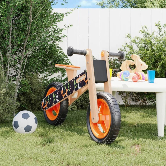 Orange and black balance bike with lightweight plywood frame and adjustable seat in backyard