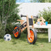 Orange and black balance bike with lightweight plywood frame and adjustable seat in backyard