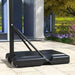 Portable adjustable basketball stand base outdoors on stone patio near modern building
