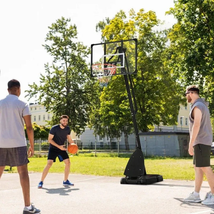 Outdoor basketball hoop with rebounder, three men playing on sunny day in park setting