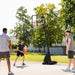 Outdoor basketball hoop with rebounder, three men playing on sunny day in park setting