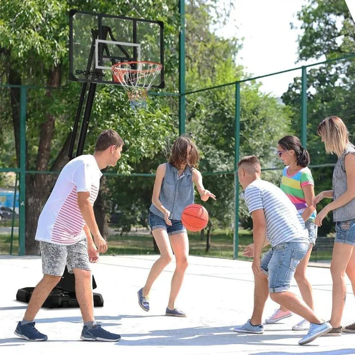 Teens playing basketball on outdoor court with adjustable basketball stand and rebounder