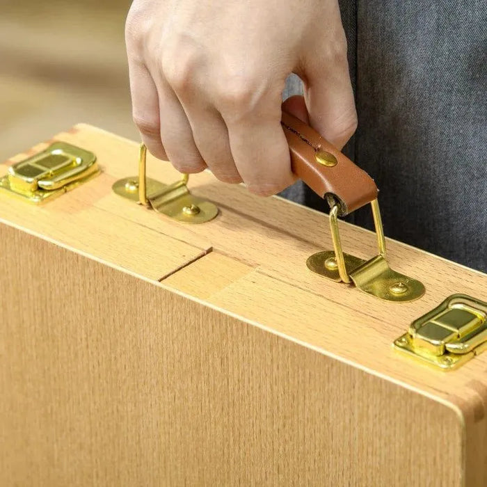 Hand holding beechwood table top easel box with gold latches and leather handle
