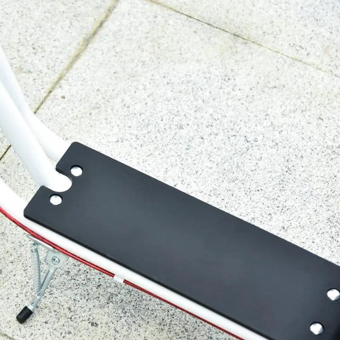 Close-up of black foot deck and white frame on kids scooter with kickstand, outdoor setting