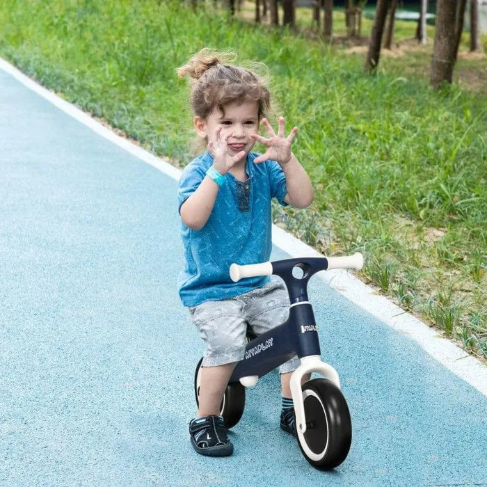 Young child riding blue kids balance bike with adjustable seat on outdoor path