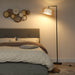 Boho LED floor lamp with woven rattan shade illuminating bedroom with gray upholstered bed and wall decor