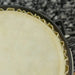 Close-up of natural sheepskin bongo drum head with metal tuning rim on textured surface