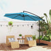Blue patio umbrella over two wicker chairs on a wooden deck with plants and string lights.
