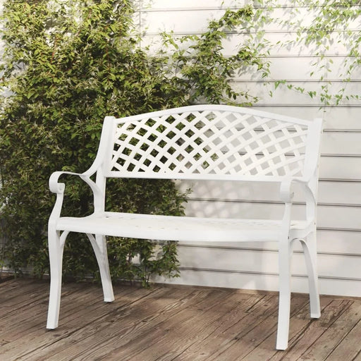 White cast aluminium garden bench with ornate lattice design on wooden patio