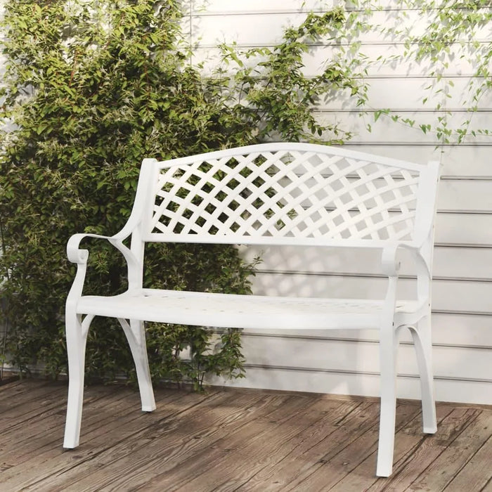 White cast aluminium garden bench with ornate lattice design on wooden patio