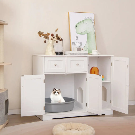 White wooden side cabinet with open doors housing a cat in a grey litter box, decorated with books, vase, lamp, and dinosaur art