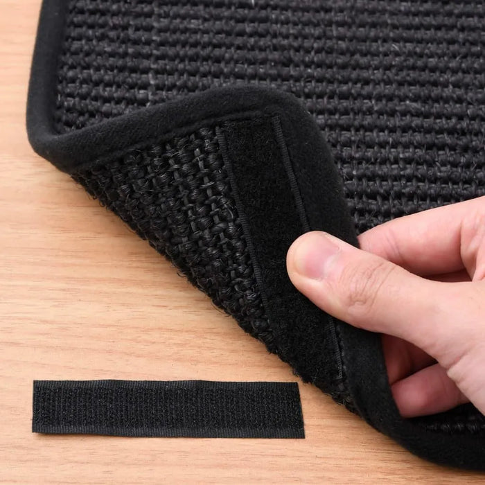 Hand lifting black woven mat with Velcro backing on wood surface, included extra Velcro strip