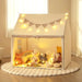 Children's indoor play tent in beige with star lights, flag banner, and plush toys inside.