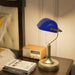 Blue lamp and vintage radio on a bedside table with books underneath.