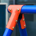 Close-up of a blue metal swing frame with orange joint and gold bolts, outdoor setting