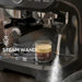 Espresso machine with steam wand and a glass of layered coffee