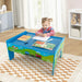 Child coloring at colorful wooden train activity table with books in a bright playroom