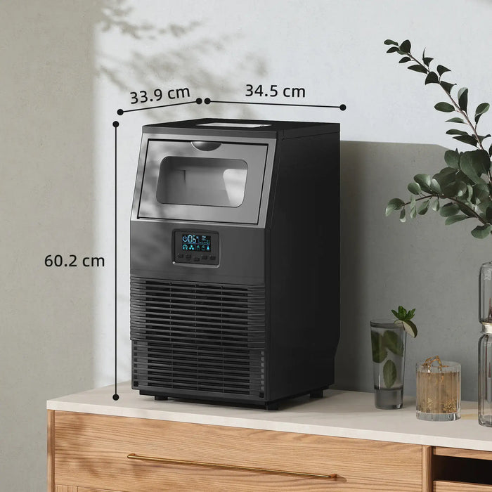 Black ice maker on a countertop with dimensions labeled, surrounded by decorative items.