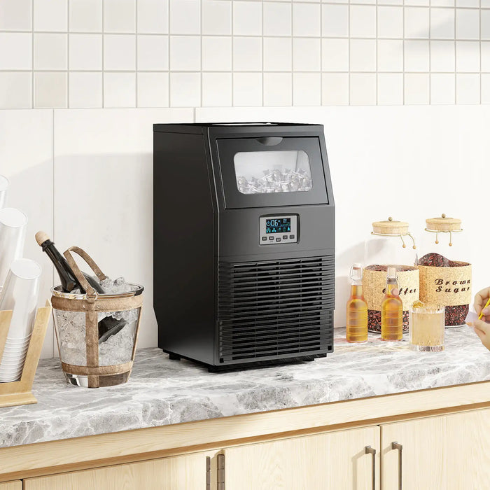 Black ice maker on a kitchen counter with various items around