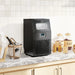 Black ice maker on a kitchen counter with various items around