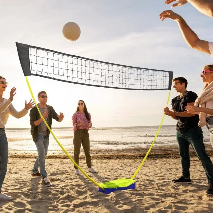 Group playing beach volleyball with portable net set by the ocean at sunset