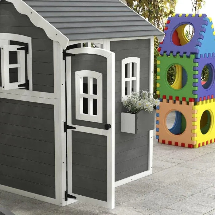 Grey wooden cottage-style playhouse with white trim and toy blocks on patio