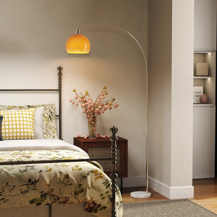 Bedroom interior with floral bedspread, nightstand, and floor lamp.