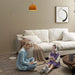 Two children in a cozy living room with a white couch and decorative lamp.