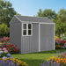 Gray metal garden shed with window and locked door surrounded by colorful flowers and green trees